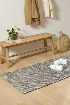 a wooden bench sitting on top of a hard wood floor next to a potted plant