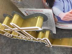 a woman sitting at a table next to a gold and black sign with scissors on it