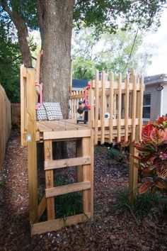 a tree house built into the side of a tree in front of a fenced yard