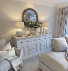 a living room filled with furniture and a large mirror on top of a dresser next to a window