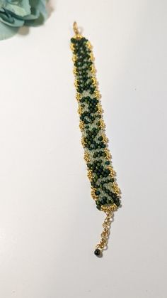 Multi-tone green beaded bracelet made with 8/0 Toho beads and gold-tone O beads for a scalloped finish, complete with a lobster clasp and extension chain. This bracelet is 6.75" long and can extend an additional 1". It has a width of 0.75" Green Beaded Chain Bracelet For Gift, Green Beaded Chain Bracelets As A Gift, Green Beaded Chain Bracelet As Gift, Green Beaded Bracelet For Gift, Adjustable Gold Beaded Bracelets Made Of Czech Glass, Green Beaded Chain Bracelets For Jewelry Making, Adjustable Green Bracelets With Gold Beads, Adjustable Gold Beaded Bracelets With Czech Glass, Green Beaded Chain Bracelet For Jewelry Making