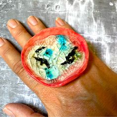 a person's hand holding a piece of fruit with blue and green designs on it