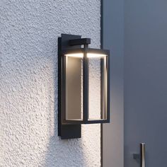 an outdoor light mounted on the side of a white stucco wall next to a door