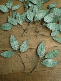 some green leaves are tied together on a wooden surface with string and paper tags attached to them