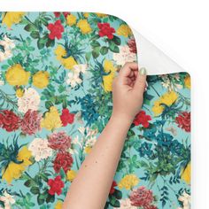 a woman's hand is touching the wallpaper on a floral print background with flowers