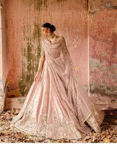 a woman in a pink gown standing next to a wall with peeling paint on it