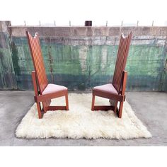 two wooden chairs sitting on top of a white rug