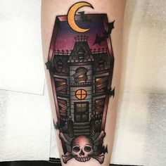 a person with a tattoo on their leg that has a skull in front of a house