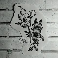 a pair of scissors with flowers on it sitting on a white brick wall next to a sticker