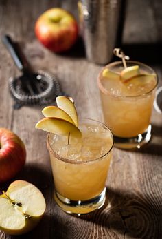 two glasses filled with apple cider on top of a wooden table