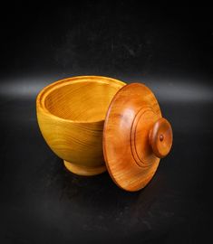 a wooden bowl with a lid sitting on a black surface