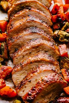 sliced pork and vegetables on a white platter with a fork next to the meat