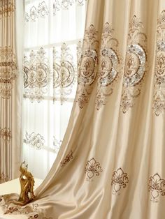 the curtains are hanging in front of the window with gold trimmings on them