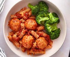 a white bowl filled with meatballs and broccoli on top of a table