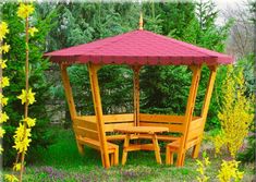 a wooden gazebo surrounded by yellow flowers and trees