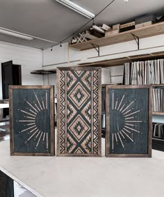 three black and white paintings sitting on top of a table next to bookshelves