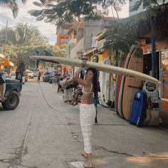 a woman carrying a surfboard down a street