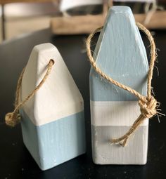 two small blue and white wooden blocks tied up to each other on a black table