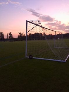 a soccer goal sitting on top of a field next to a green grass covered field