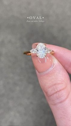 a woman's hand holding an engagement ring with a spider on it and the words oval above it