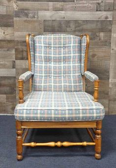 an upholstered chair with blue and white plaid fabric on it, against a wooden wall