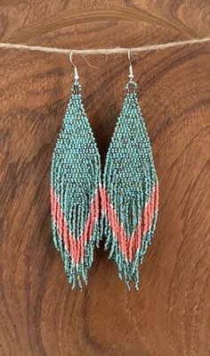 two pairs of beaded earrings hanging from a string on top of a wooden surface