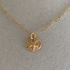 A sand dollar coin dangles from a delicate gold chain. The chain measures approximately 17 inches long is adjustable up to an inch shorter. Adjustable Gold Medallion Charm Necklaces, Gold Adjustable Round Disc Charm Necklaces, Gold Medallion Charm Necklace, Gold Coin Necklace With Adjustable Chain For Everyday, Adjustable Gold Medallion Necklace With Round Pendant, Adjustable Gold Medallion Necklace, Adjustable Gold Coin Necklace, Gold Adjustable Medallion Necklace With Round Pendant, Nickel-free Yellow Gold Medallion Coin Necklace