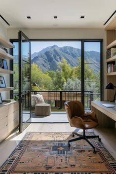 an office with a desk, chair and bookcase in front of a mountain view