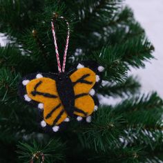 an ornament hanging from a christmas tree with a yellow and black butterfly on it