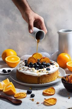 a person pouring oranges into a cake on a table with other fruits and condiments