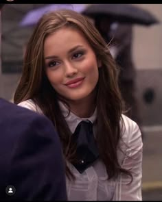 a woman with long brown hair wearing a white shirt and black tie