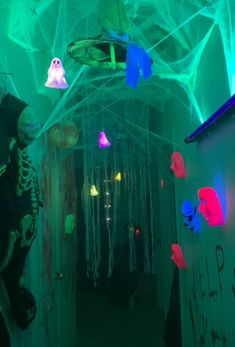 the hallway is lit up with colorful lights and ghost decorations on the walls, along with other halloween decorations