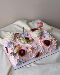 a pink cake with flowers on it sitting on a white sheet