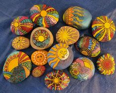 painted rocks with sun and moon designs on blue fabric background, closeup view from above