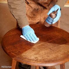 a person in blue gloves wiping down a wooden table