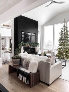 a living room filled with furniture and a fire place next to a christmas tree on top of a hard wood floor