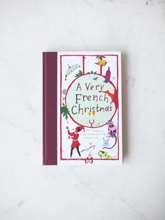 a very french christmas book sitting on top of a white table next to a red cover