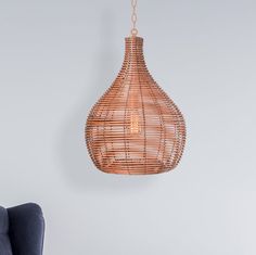 a rattan light hanging from the ceiling next to a blue chair and ottoman in a living room