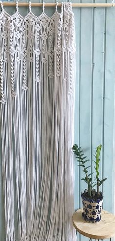 a macrame wall hanging next to a potted plant on a small table