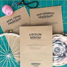 three book covers sitting on top of a cutting board next to yarn and scissors,