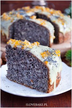 a slice of chocolate cake on a white plate with orange zest and nuts around it