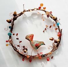 a bird sculpture made out of branches with beads and leaves on it's sides