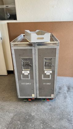 two metal lockers sitting next to each other on top of a cement floor in front of a wall