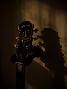 an acoustic guitar is shown in the dark with its shadow on the wall behind it