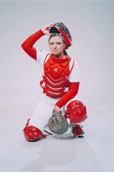 a woman sitting on the ground with a baseball glove and catchers mitt in her hand