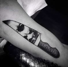 a black and white photo of a knife on the arm with a woman's face