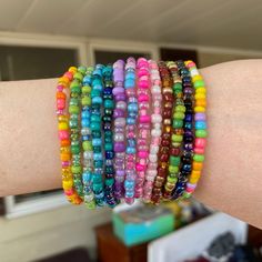 a woman's arm with several bracelets on it, all in different colors