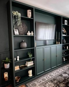 a living room filled with lots of green bookshelves next to a black wall