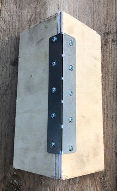 a piece of wood with metal rivets on it sitting on top of a wooden floor