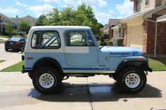 a blue and white jeep parked in front of a house